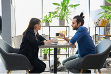 Deux personnes face à face discutant autour d'une table